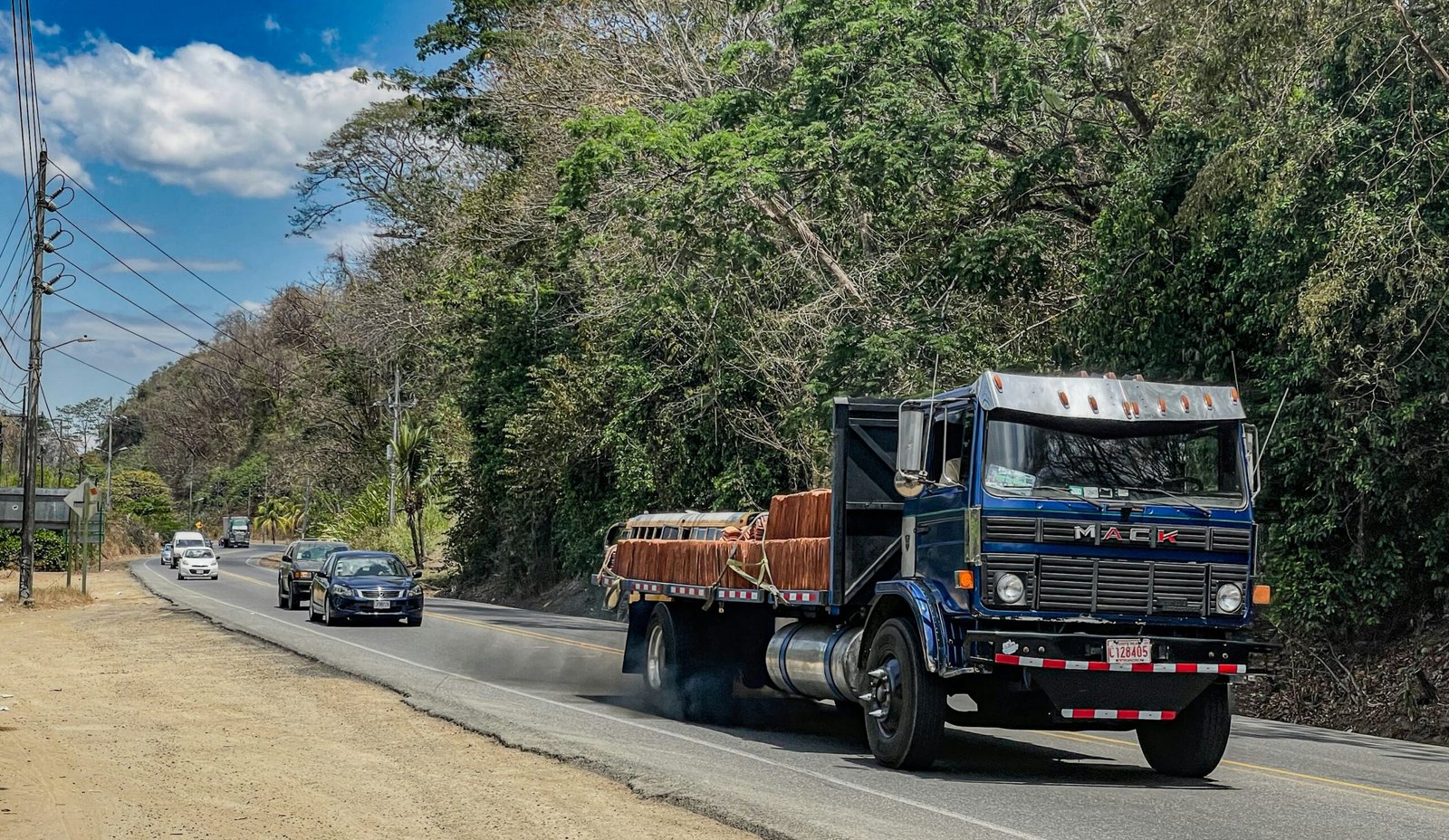 a truck driving down a road next to a forest