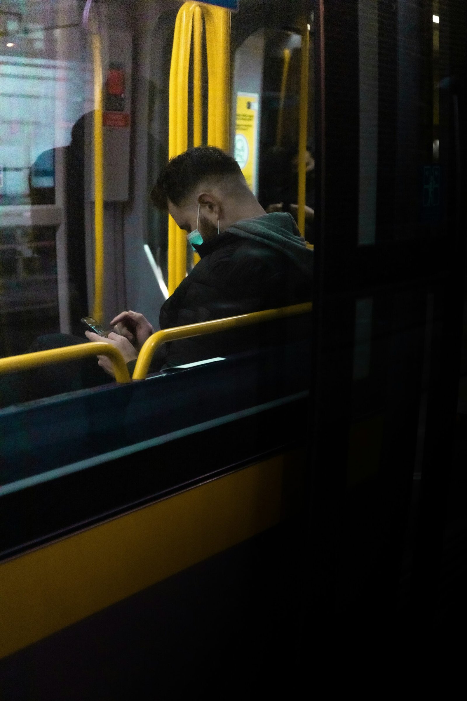 man in black jacket sitting on yellow and blue train seat